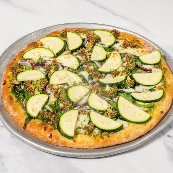 Ristorante da Maria's Italian pizza with zucchini, red onion, broccoli, and spinach on a metal pan.