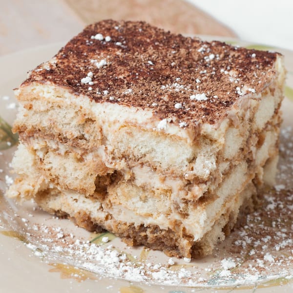 A slice of Ristorante da Maria's tiramisu, dusted with cocoa and powdered sugar, on a patterned plate.